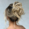 Blonde hair bun styled in an updo against a plain background