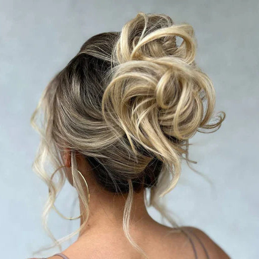 Blonde hair bun styled in an updo against a plain background