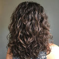 Curly hair styled in a way that highlights its texture and volume against a neutral background.