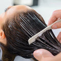 Person getting hair treatment with a comb in a salon setting