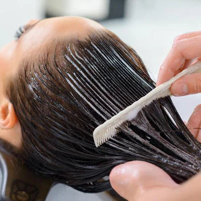 Person getting hair treatment with a comb in a salon setting
