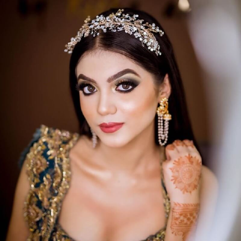 Woman in traditional attire with jewelry and henna, blurred background