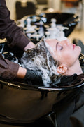 Person getting a hair wash at a salon with soapy hair.