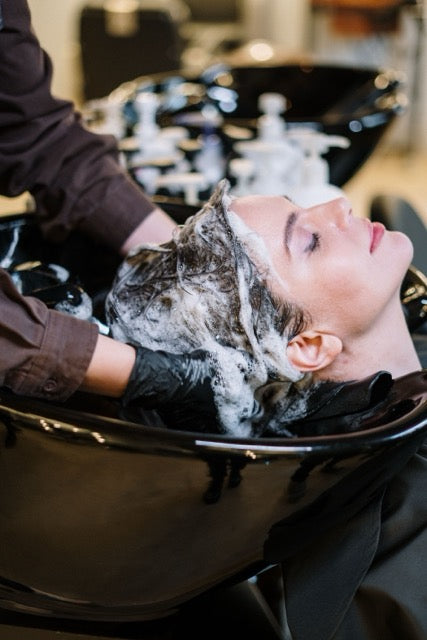 Person getting a hair wash at a salon with soapy hair.