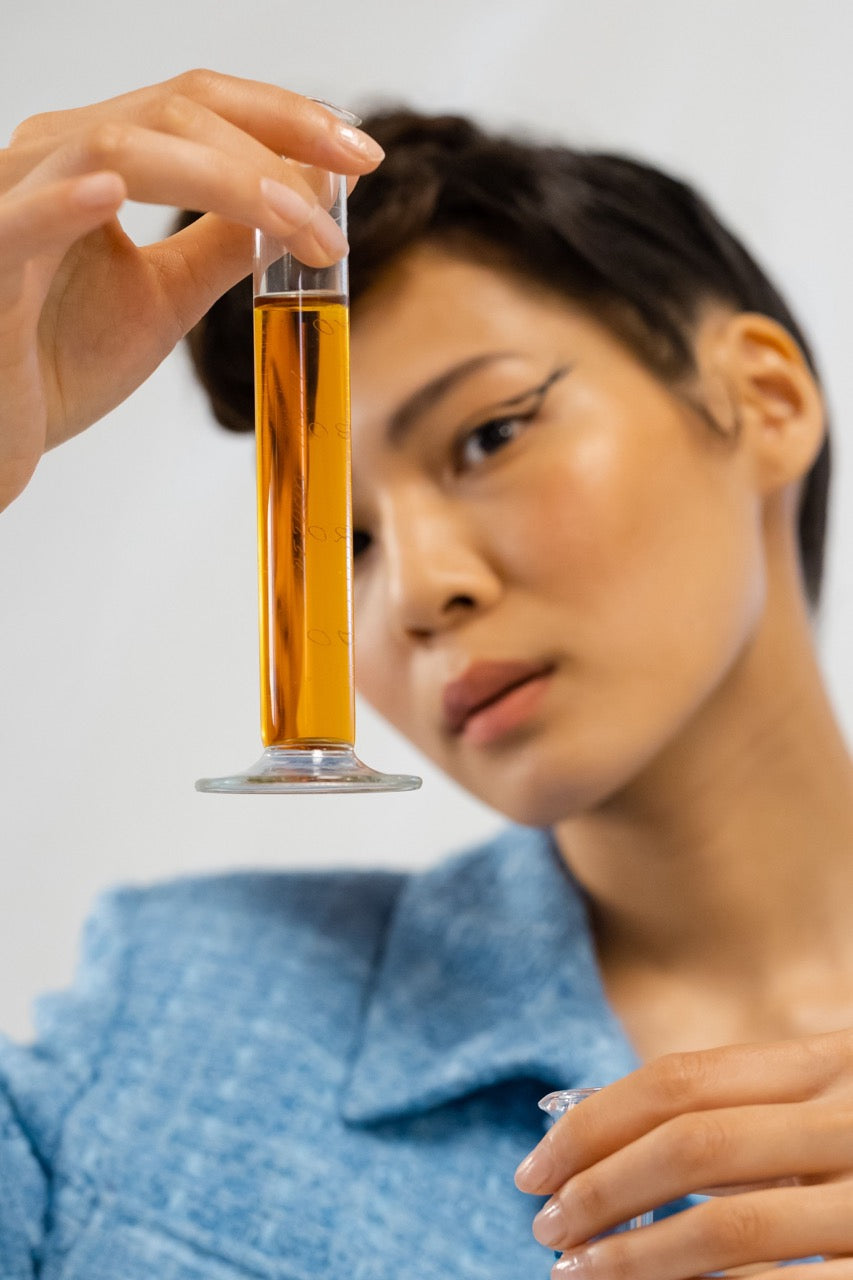 Woman holding a glass with amber liquid against a white background