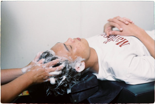 Person getting a hair wash with shampoo on a white background