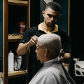 Barber styling a customer's hair in a barbershop.