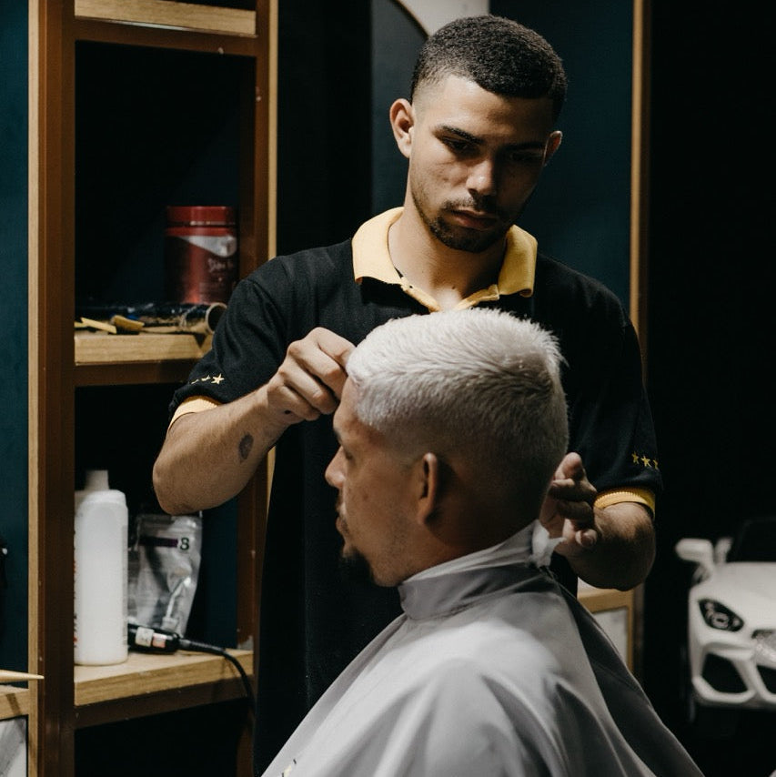 Barber styling a customer's hair in a barbershop.