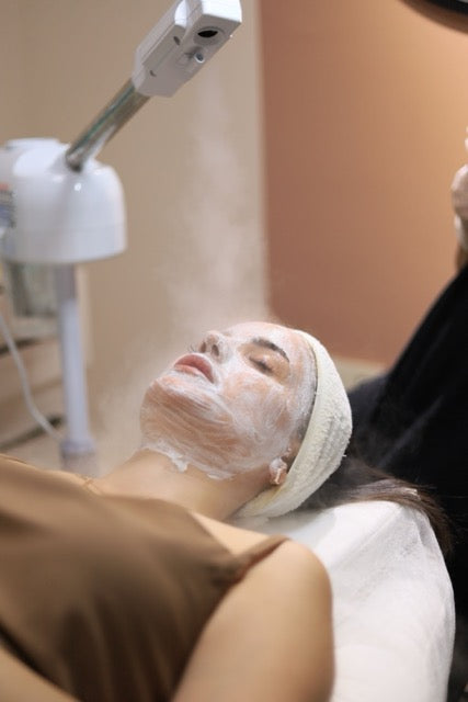 Person receiving a facial treatment with a machine above their head.