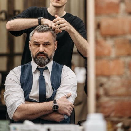 Man getting a haircut in a barbershop with a brick wall background