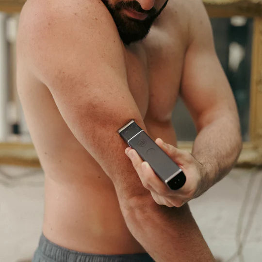 Man using an electric razor on his arm with a mirror in the background